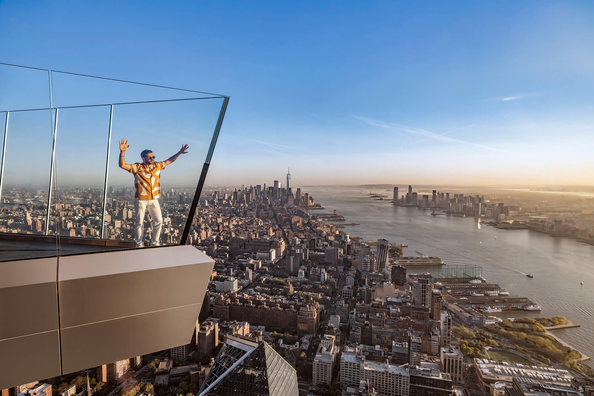 A man strikes a pose at The Edge overlooking New York City at sunset