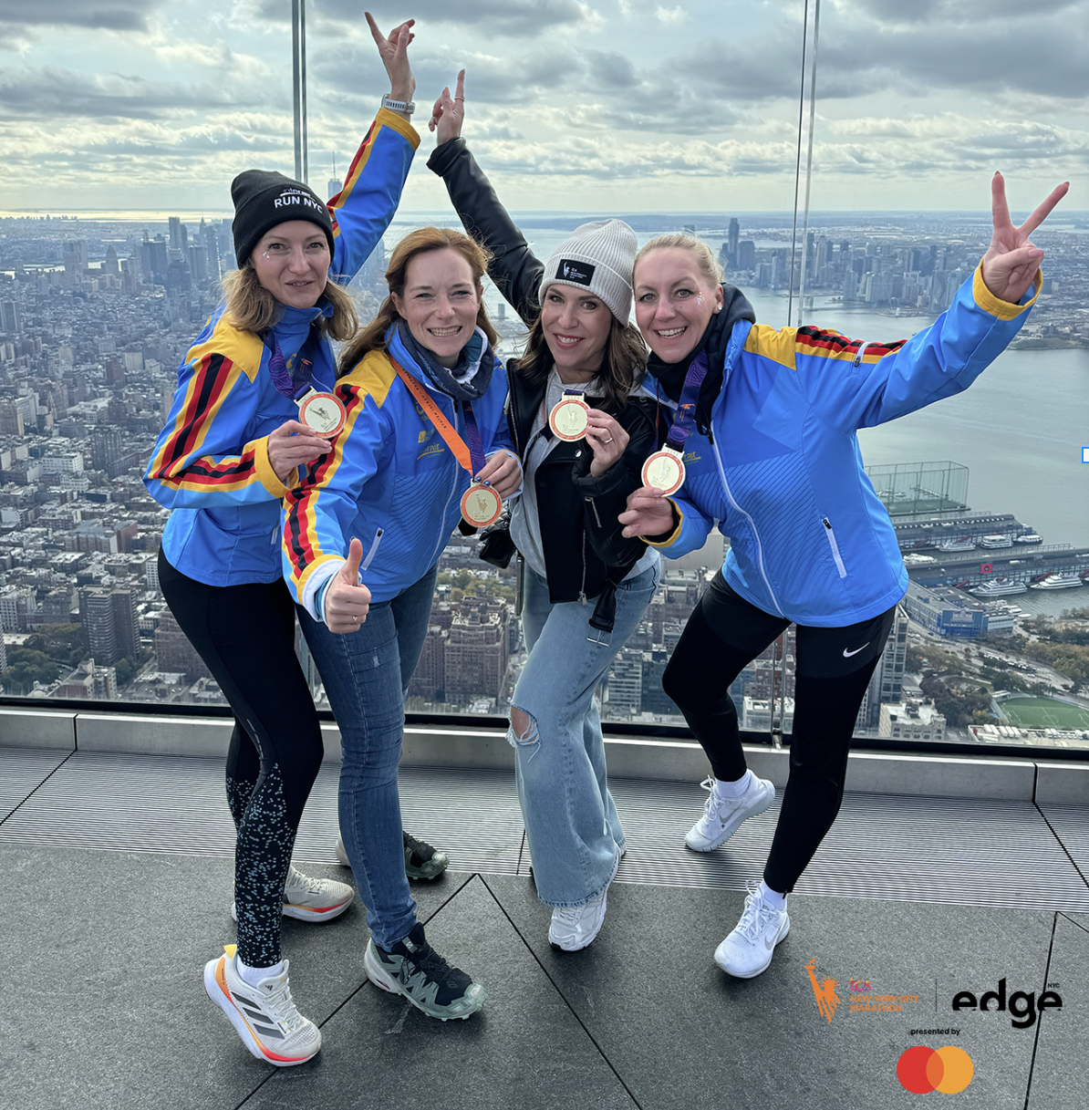 four runners posing for a picture at the top of the edge nyc